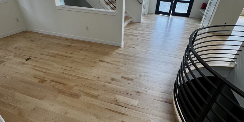 Refinished maple hardwood entry with curved black stair railing in a Kirkland, WA home